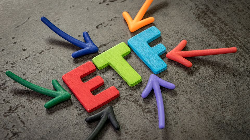 ETF, exchange-traded fund an investment fund traded on stock exchanges concept, multi color arrows pointing to the word ETF at the center of black cement chalkboard wall.