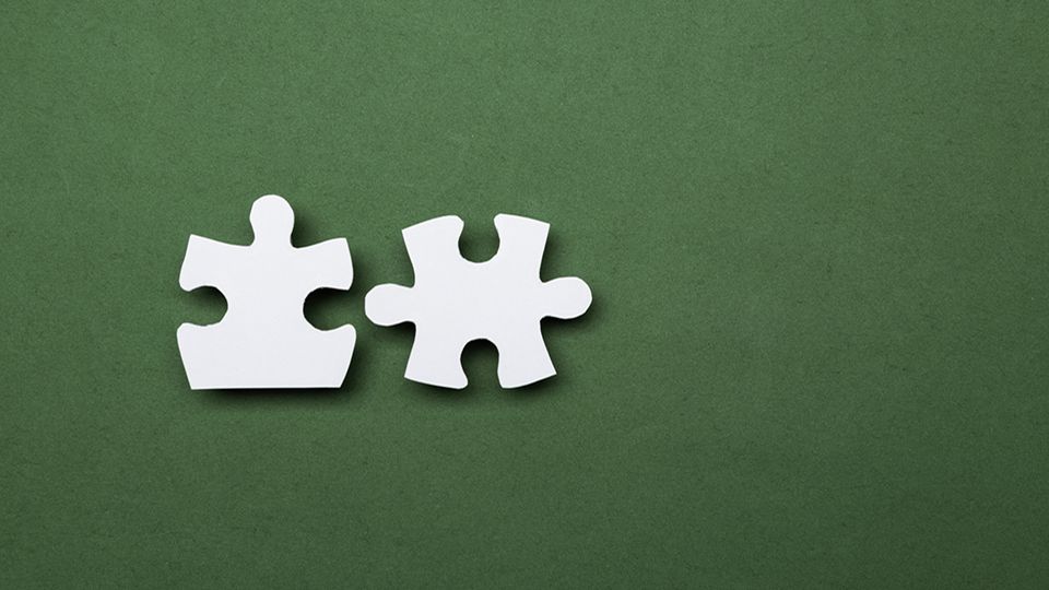 Two puzzle pieces merging and joining together on green background