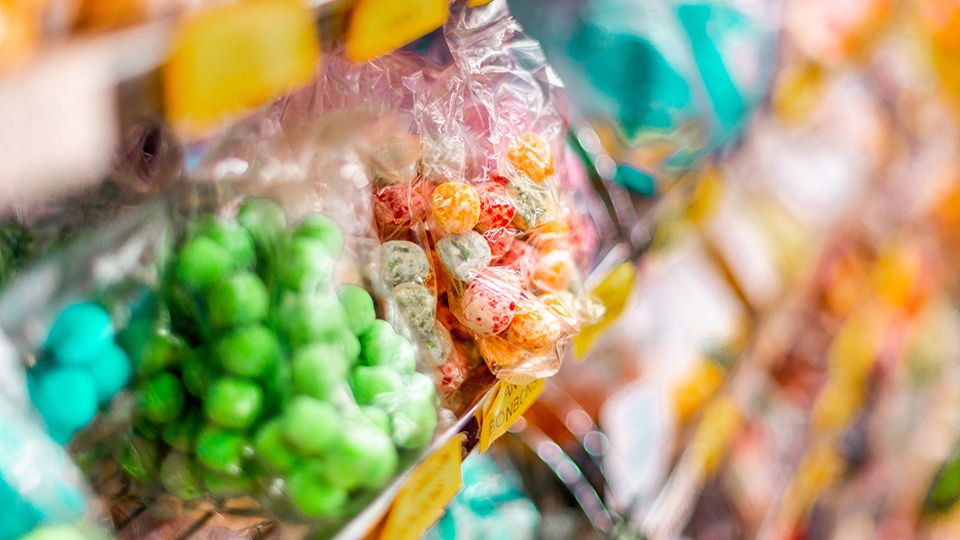 Tasty looking green, red and yellow Sweets and Candy in a wrapper on a shelf of a sweet shop in Matlock, UK