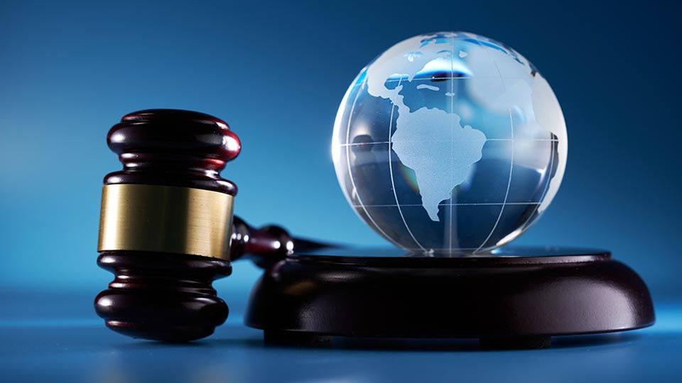 gavel hammer and glass globe against blue background