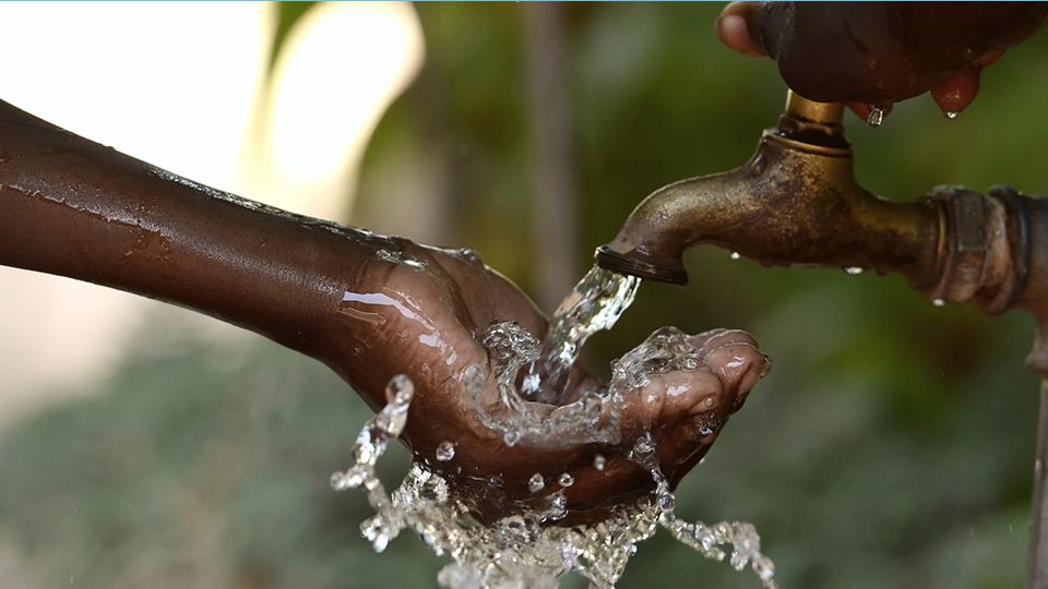 Hand of an African child with water pouring from a tap.
