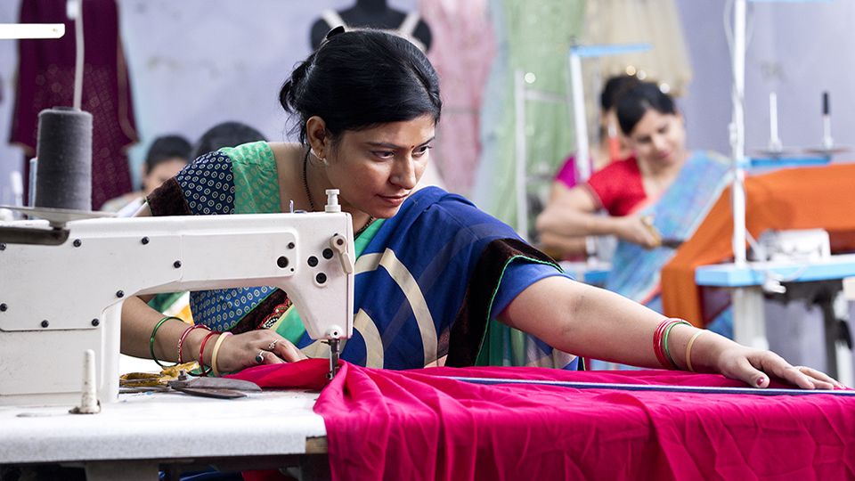 Indian woman textile worker using sewing machine on production line