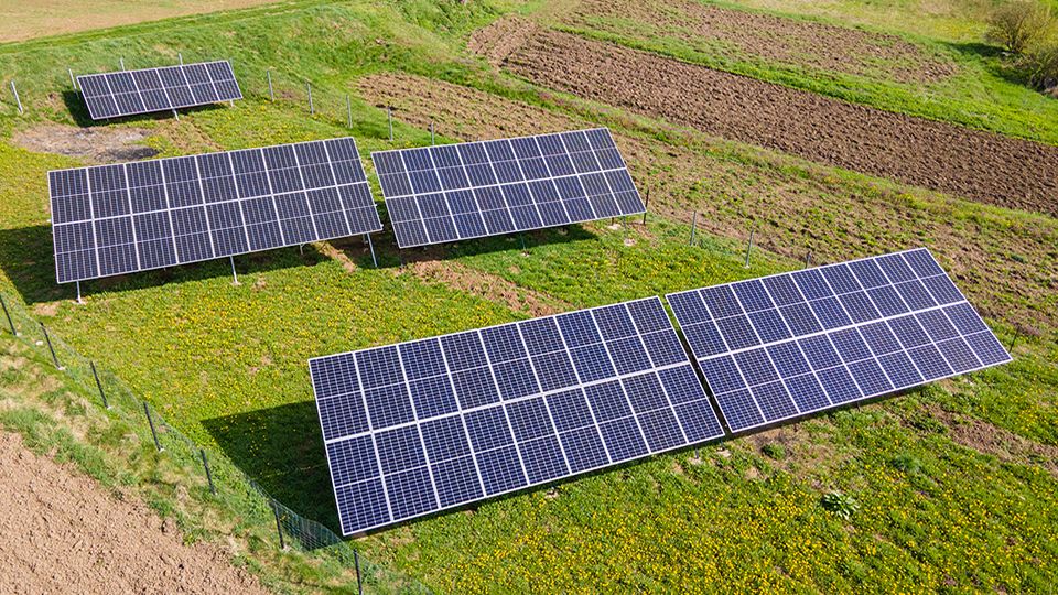Aerial view of blue photovoltaic solar panels mounted on backyard ground for producing clean ecological electricity. Production of renewable energy concept.