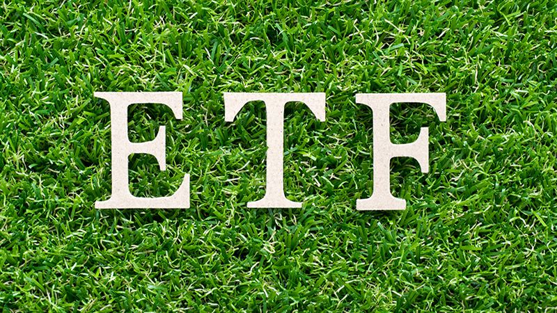 Wood alphabet in word ETF (abbreviation of Exchange Traded Fund) on artificial green grass background