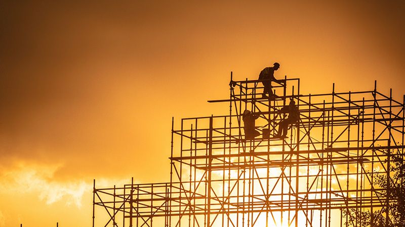 Silhouette of construction workers by sundown in Doha.