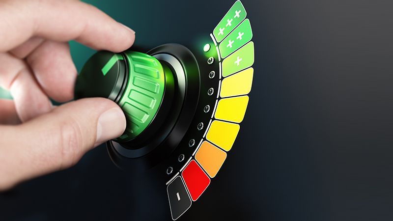 Hand turning a knob with efficiency scale from black and red to green color. Composite image between a hand photography and a 3D background.