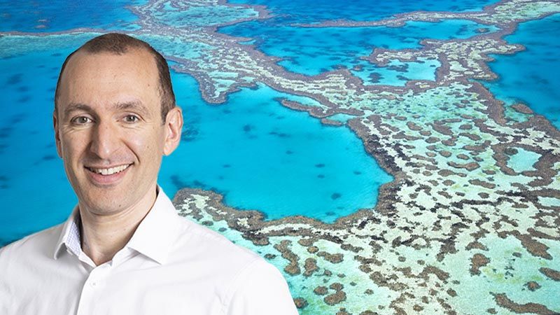 Roger Lewis against a backdrop of an aerial view of the Great Barrier Reef in Australia