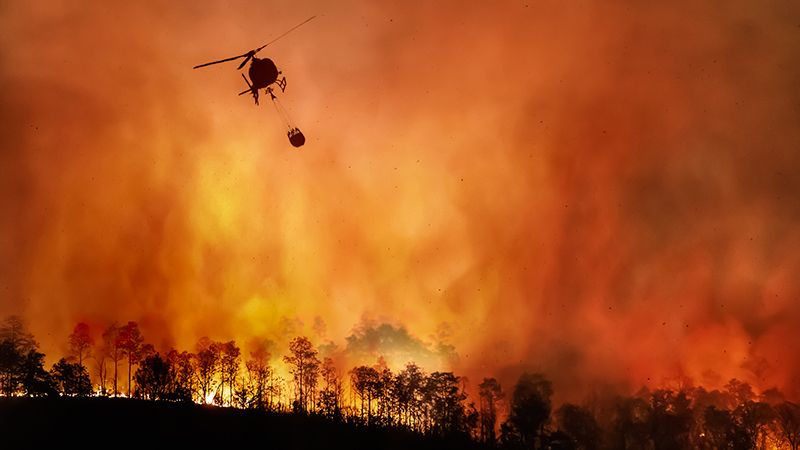 Fire fighting helicopter carry water bucket to extinguish the forest fire