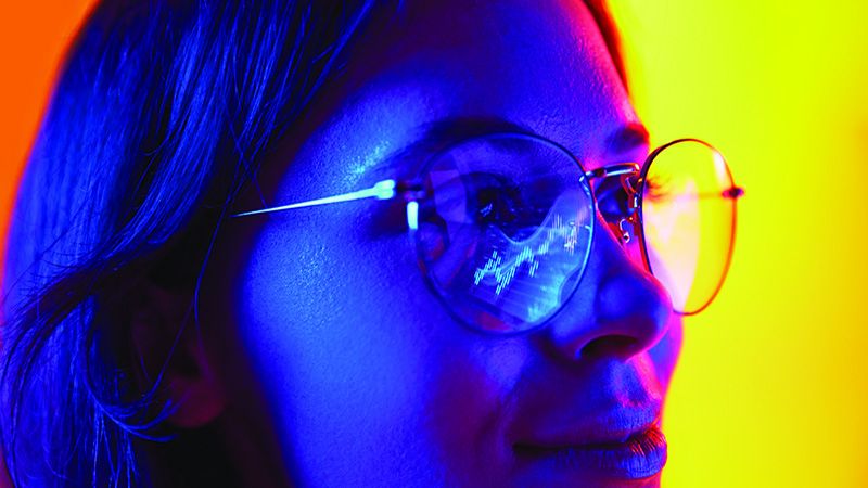 Close up portrait of young business woman in eyeglasses working in office on laptop, reflection of computer screen in glasses. Concept of technology progress, working online, using internet. Ad