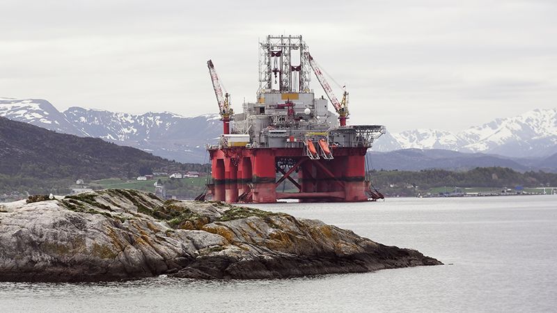 Oil rig in norwegian fjord landscape